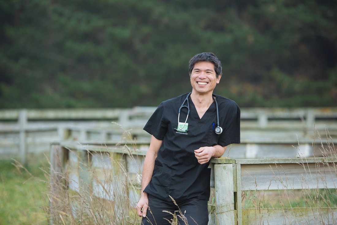 Dr Yan Wong leans on a fence post